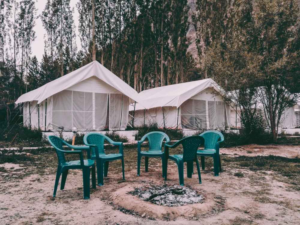 five green plastic armchairs near canopy tents